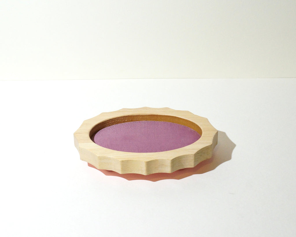 Side view of a handmade oval wooden jewelry tray with a natural wood finish, scalloped edges, and soft mauve pink brushed linen lining.