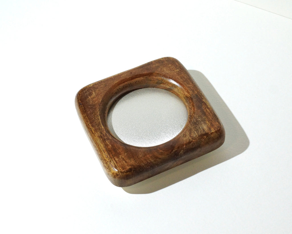 Small square wooden jewelry tray with rounded corners, a rich brown finish, visible wood grain, and a circular center lined with shimmering ivory satin fabric photographed on a white background.